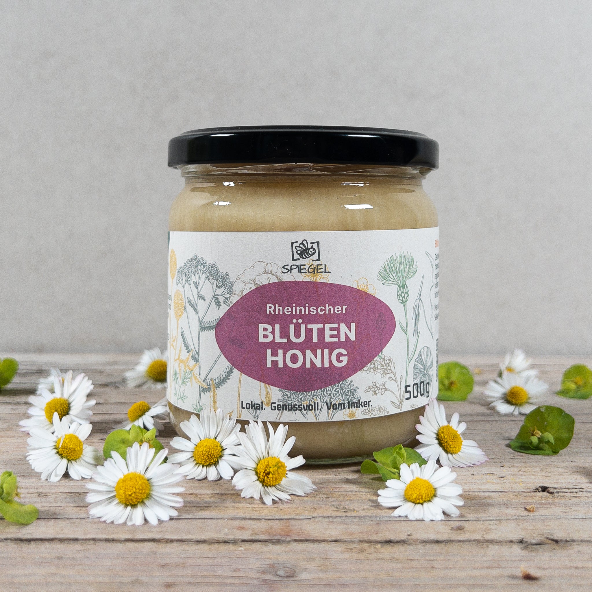 Glas Rheinischer Blütenhonig Imkerei Spiegel auf Holzplatte mit frischen Blüten.